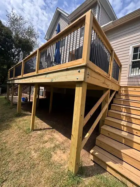Wood deck framing and posts under construction against the side of a house