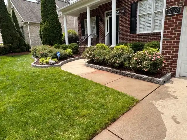 Brick home with a trimmed front lawn and a curved foundation bed of flowering shrubs