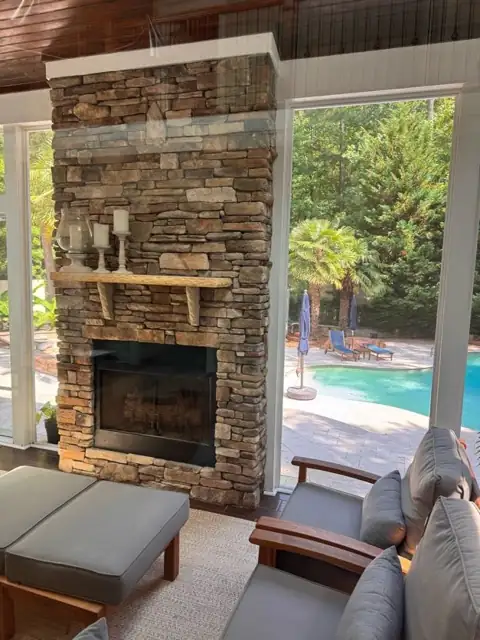 Stacked-stone outdoor fireplace on a covered porch with wood ceiling