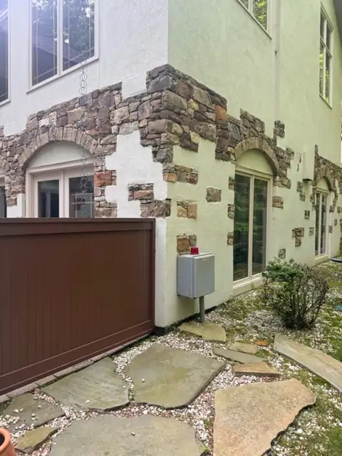 Stacked-stone veneer wall and flagstone paving beside a brown garage door